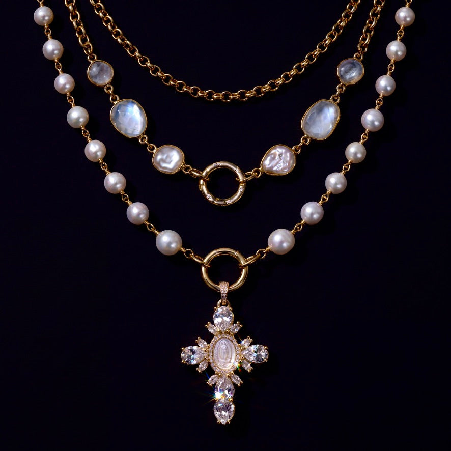 Gold moonstone and pearl necklace layering set with crystal cross pendant on black.