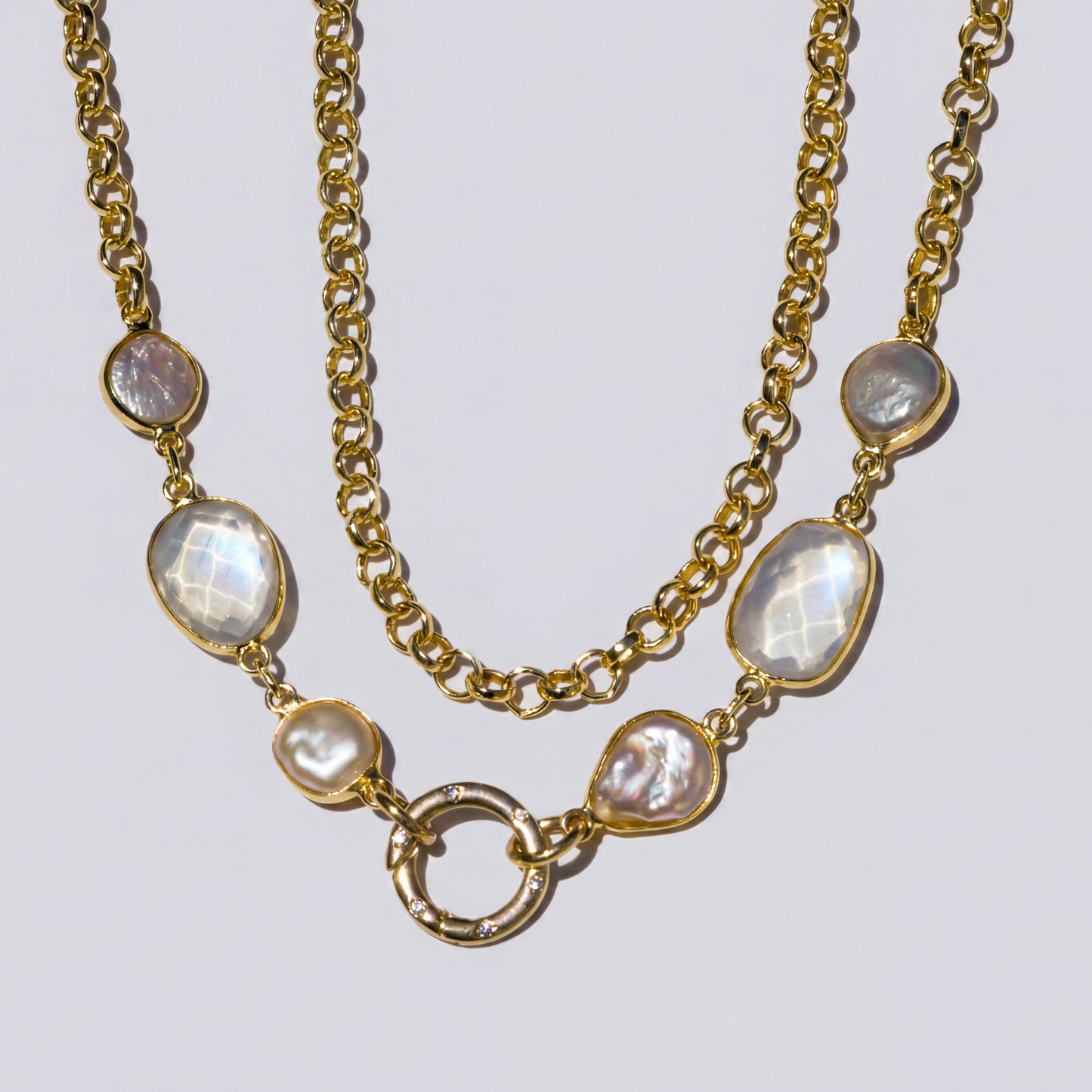 Gold necklace with gemstones on a light gray background