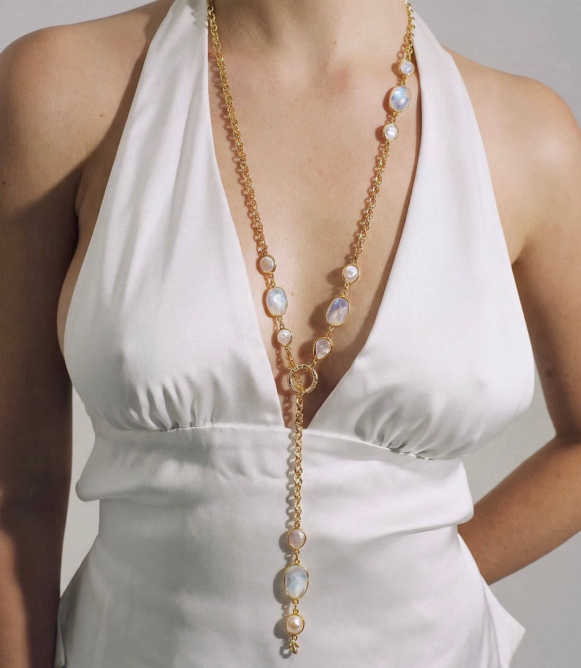 IRIS gold moonstone and pearl necklace worn as a lariat with a white halterneck top.