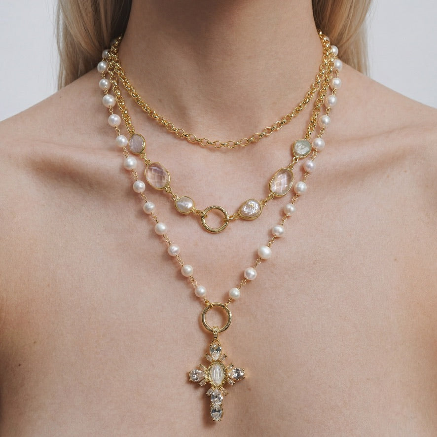 Gold moonstone and pearl necklace layering set worn with the crystal cross below two front lock clasps.