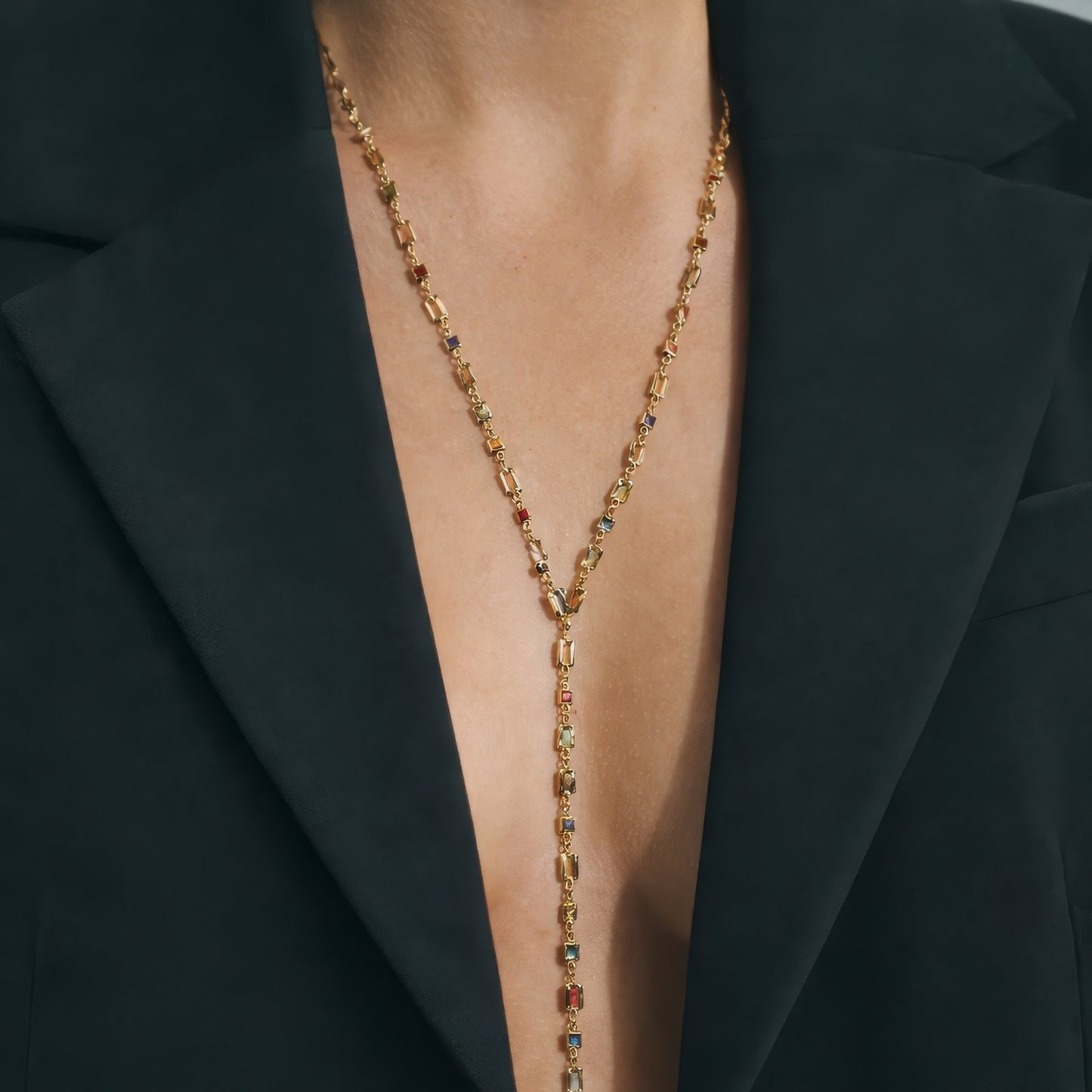 Gold necklace with gemstones worn under a black blazer