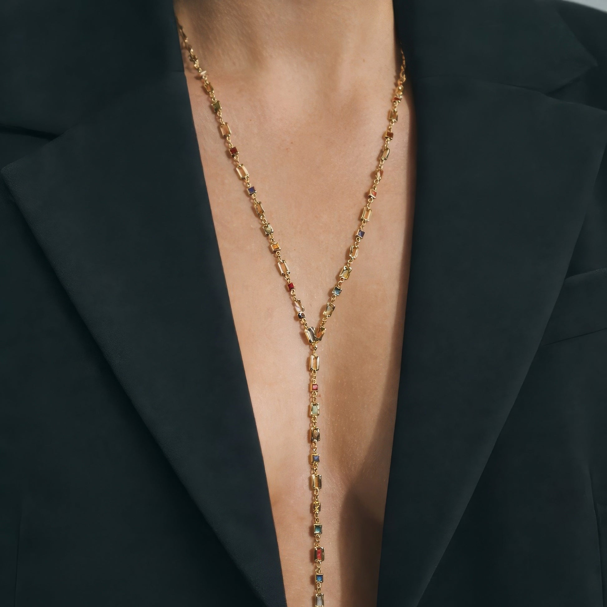 Gold necklace with gemstones worn under a black blazer
