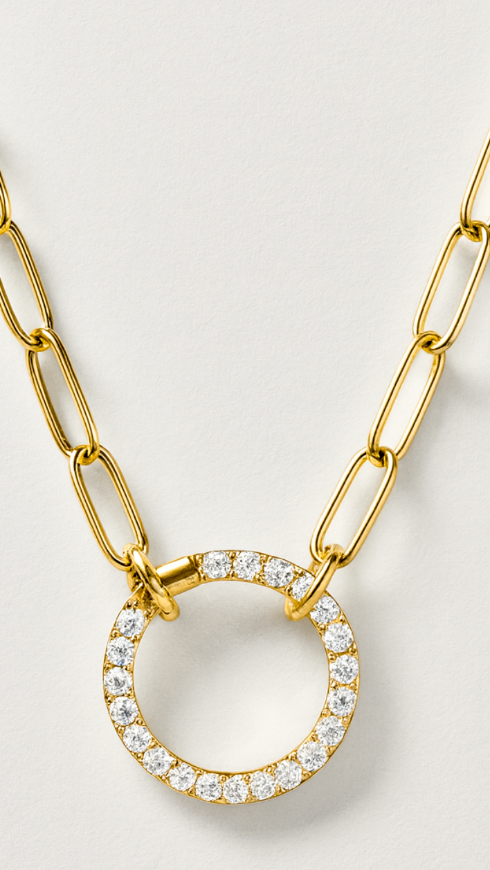 Gold necklace with a circular pendant featuring crystals on a light gray background