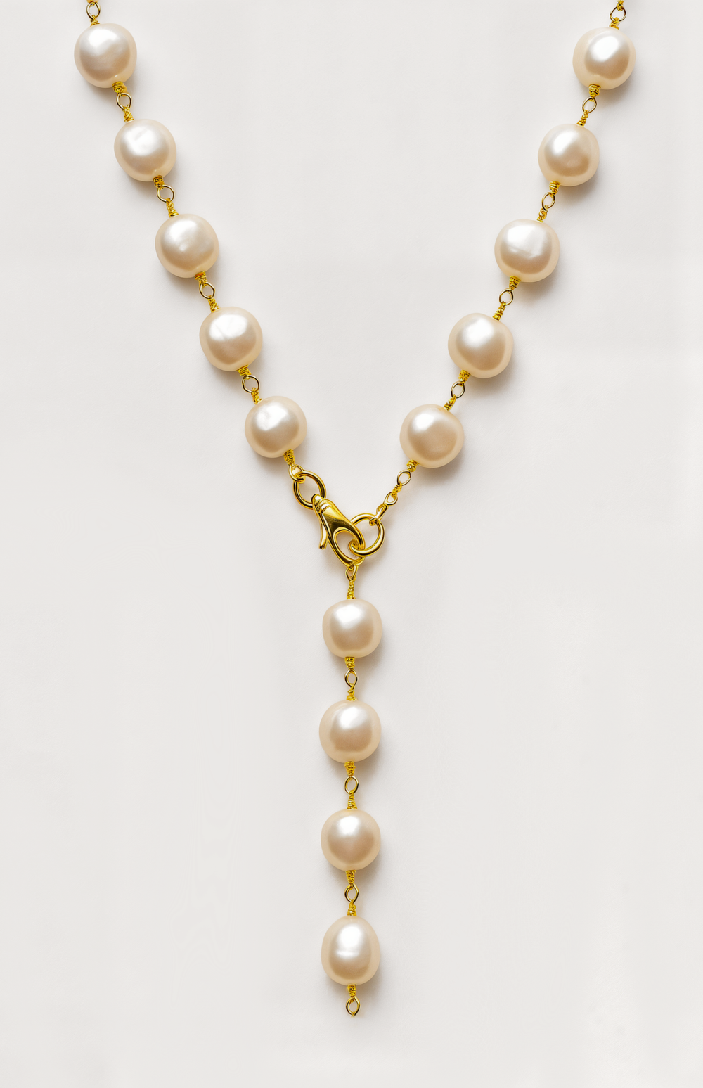 Pearl necklace with gold clasp on a light gray background