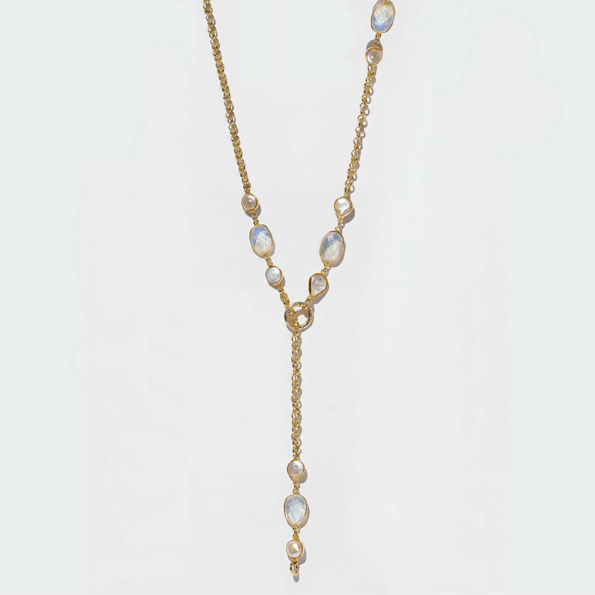 A gold Y-shaped lariat necklace featuring irregular white opal-like gemstones, displayed against a clean white background.