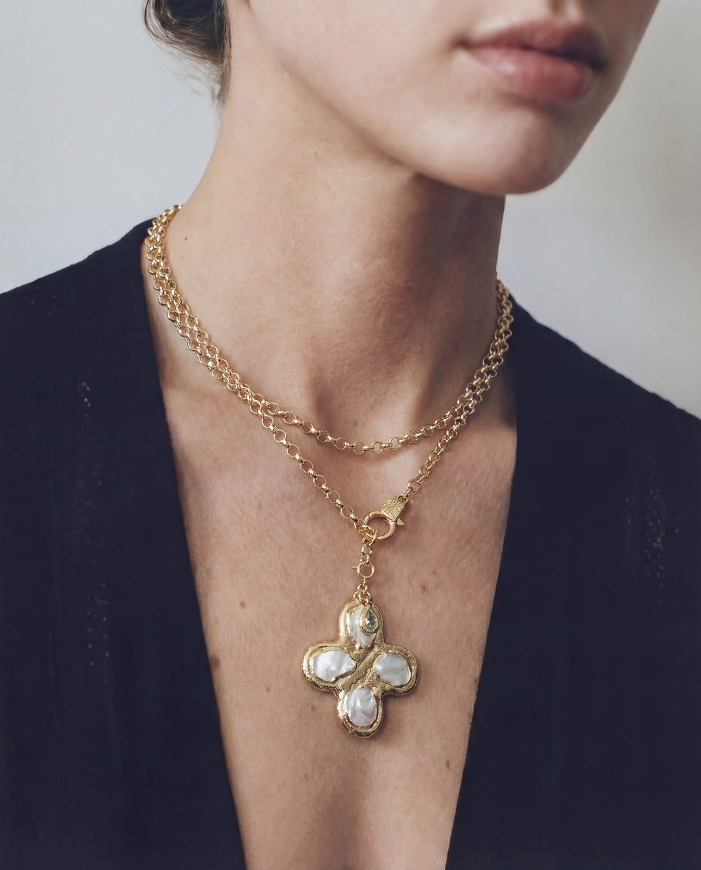 Gold necklace with a butterfly pendant worn by a person against a neutral background