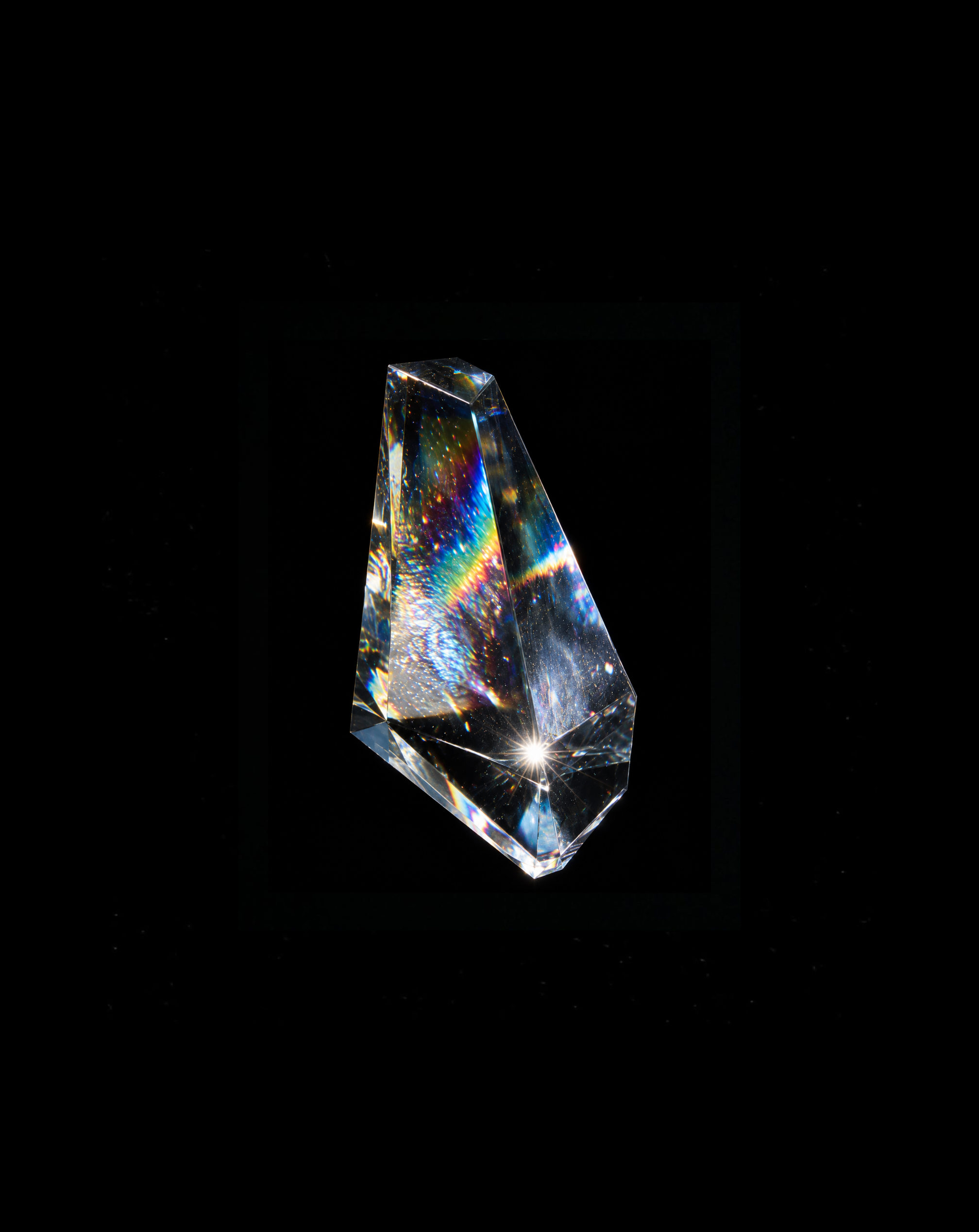 Faceted clear crystal with rainbow refractions against black