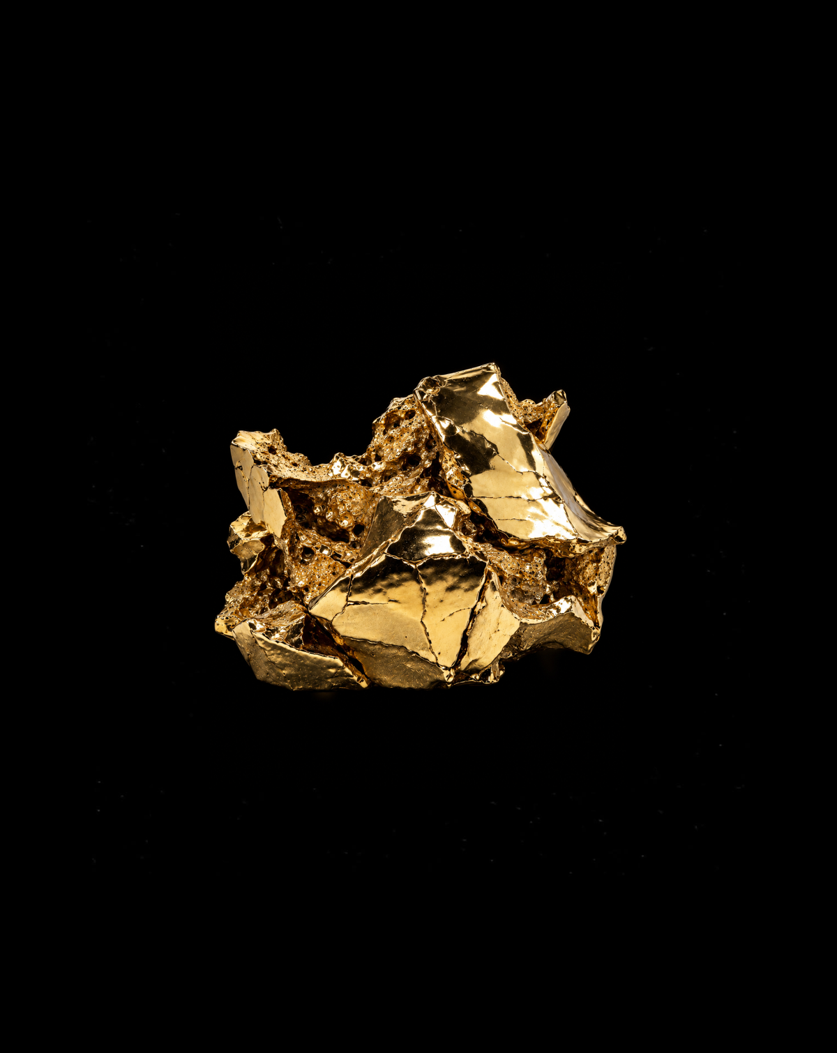Abstract polished gold metal sculpture against black