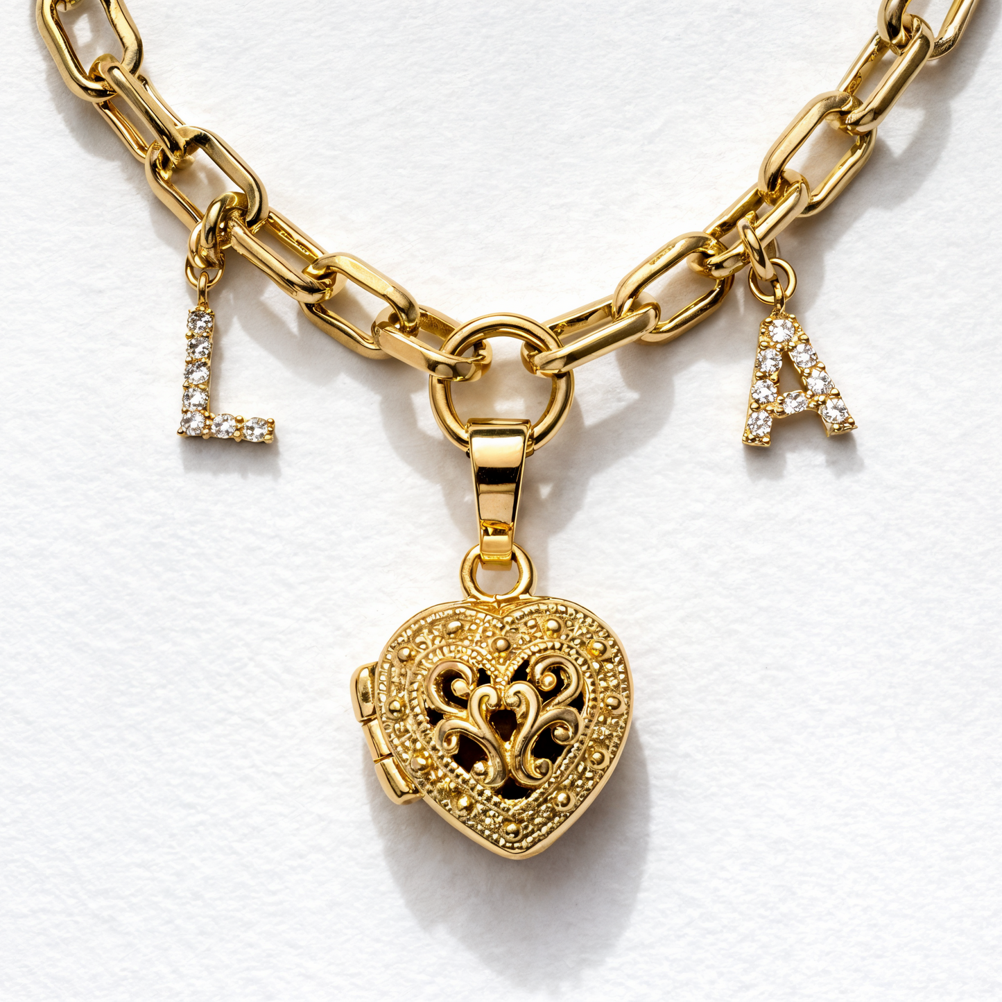 Gold chain bracelet with heart-shaped lock charm on a white background